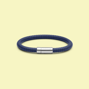 The Signature Bracelet in blue with stainless steel clasp. FKM fluoroelastomer rubber – Fully waterproof. Yellow background.