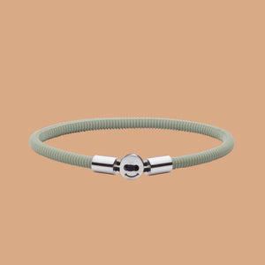 The Smile bracelet in light green Silicon Rubber with stainless steel button clasp. Fully waterproof. Beige background.