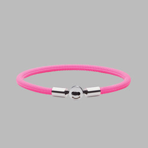 The Smile bracelet in Neon Pink Silicon Rubber with stainless steel button clasp. Fully waterproof. Coloured background.