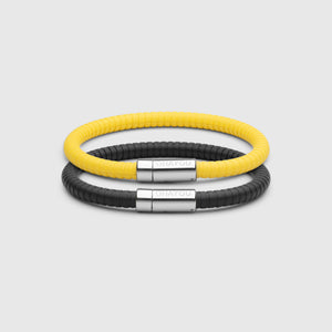  The Signature Bracelet in black with stainless steel clasp. FKM fluoroelastomer rubber – Fully waterproof. Bundled together with the Signature Bracelet in yellow on white background.