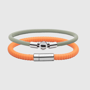 The Signature Bracelet in orange with stainless steel clasp. FKM fluoroelastomer rubber – Fully waterproof. Bundled together with the Smile Bracelet in Light Green in silicon rubber, White background.