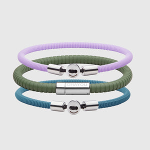 The Signature Bracelet in green with stainless steel clasp. FKM fluoroelastomer rubber – Fully waterproof. Bundled together with the Smile Bracelet in Lavender and Teal Blue in silicon rubber, and White background.