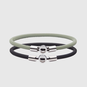 The Smile bracelet in Light Green Silicon Rubber with stainless steel button clasp, bundled with Silica Bracelet in black. Fully waterproof. White background.