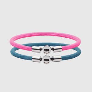 The Smile bracelet in Teal Blue Silicon Rubber with stainless steel button clasp, bundled with Smile Bracelet in Neon Pink Fully waterproof. White background.