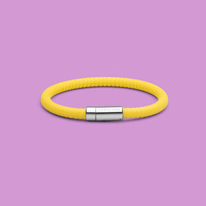The Signature bracelet in yellow with stainless steel clasp. FKM fluoroelastomer rubber – Fully waterproof. Purple background.